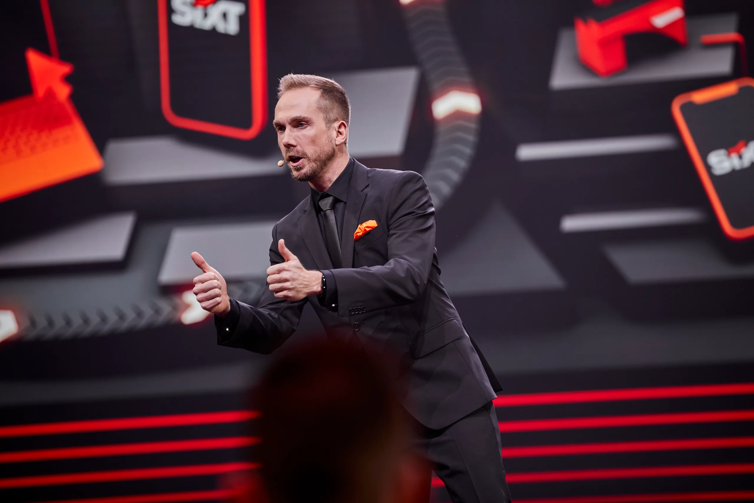 Felix Uhlig erklärt etwas auf der Bühne der SIXT World Conference 2024 in Wien