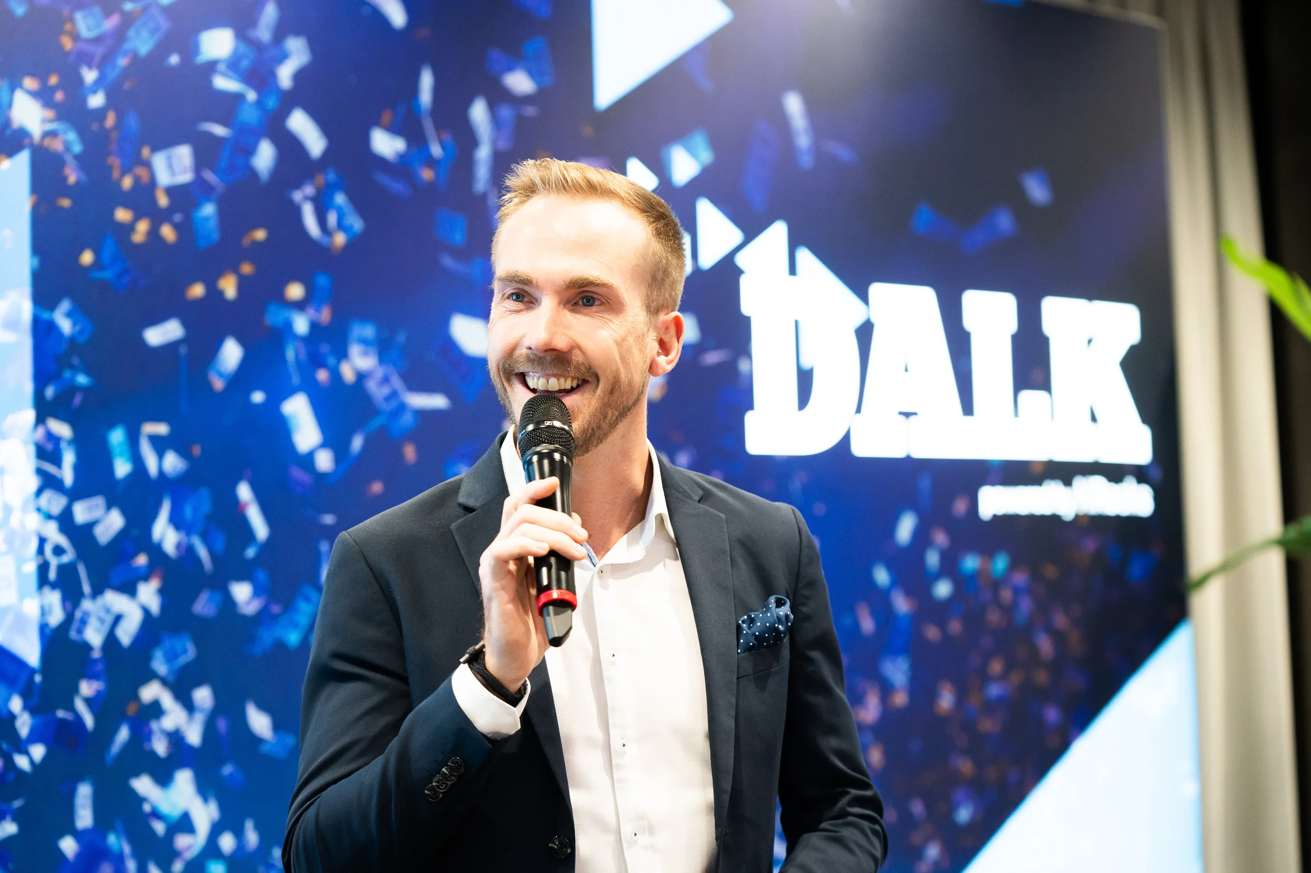 Felix Uhlig am Mikrofon vor dem Logo des Deutschen Ausbildungsleitungskongresses 2023 in Düsseldorf