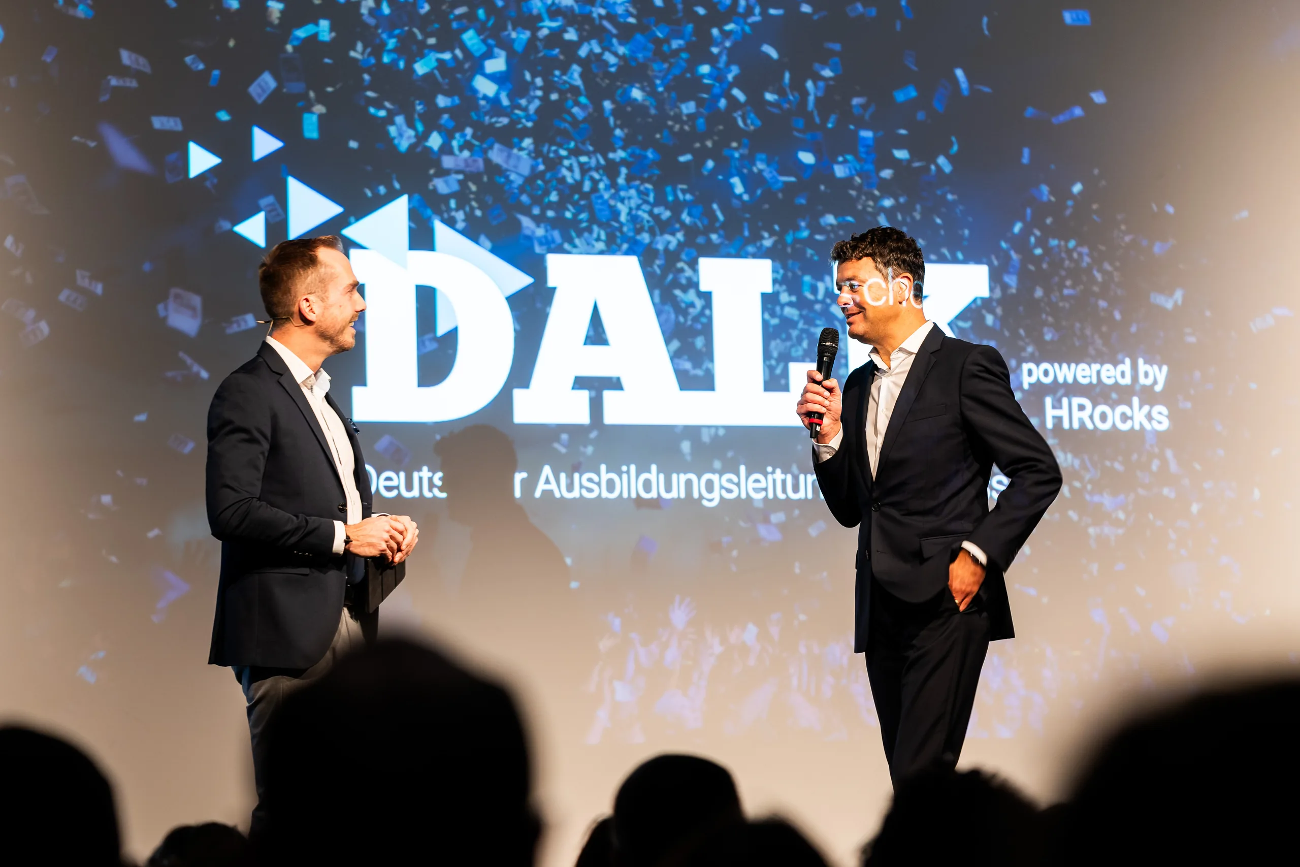 Felix Uhlig im Bühnengespräch vor der DALK-Wand beim Deutschen Ausbildungsleitungskongress 2023 in Düsseldorf