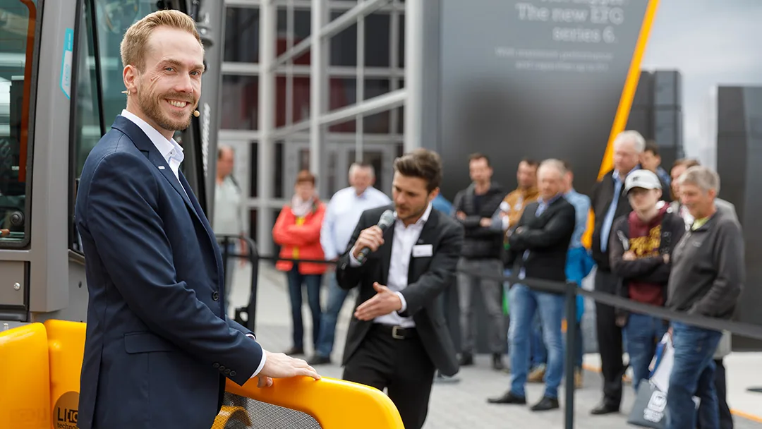 Felix Uhlig an einem Jungheinrich-Flurförderzeug vor Messebesuchern bei der BAUMA 2019 in München