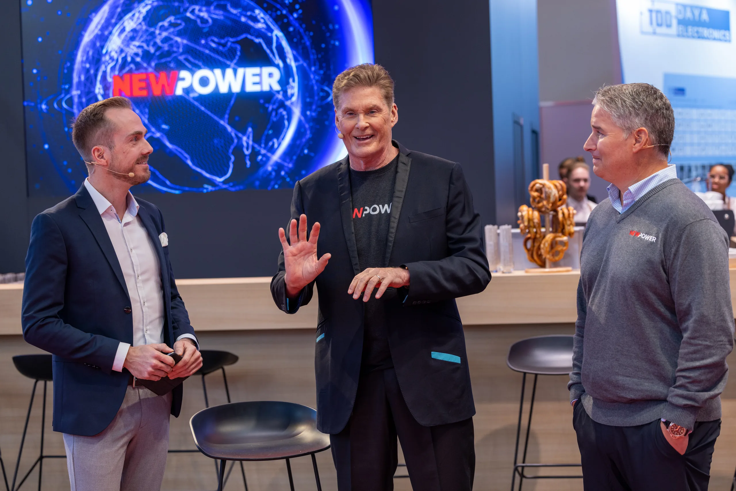 Felix Uhlig im Gespräch mit David Hasselhoff und einem weiteren Gast am NewPower-Stand der Electronica 2022 in München