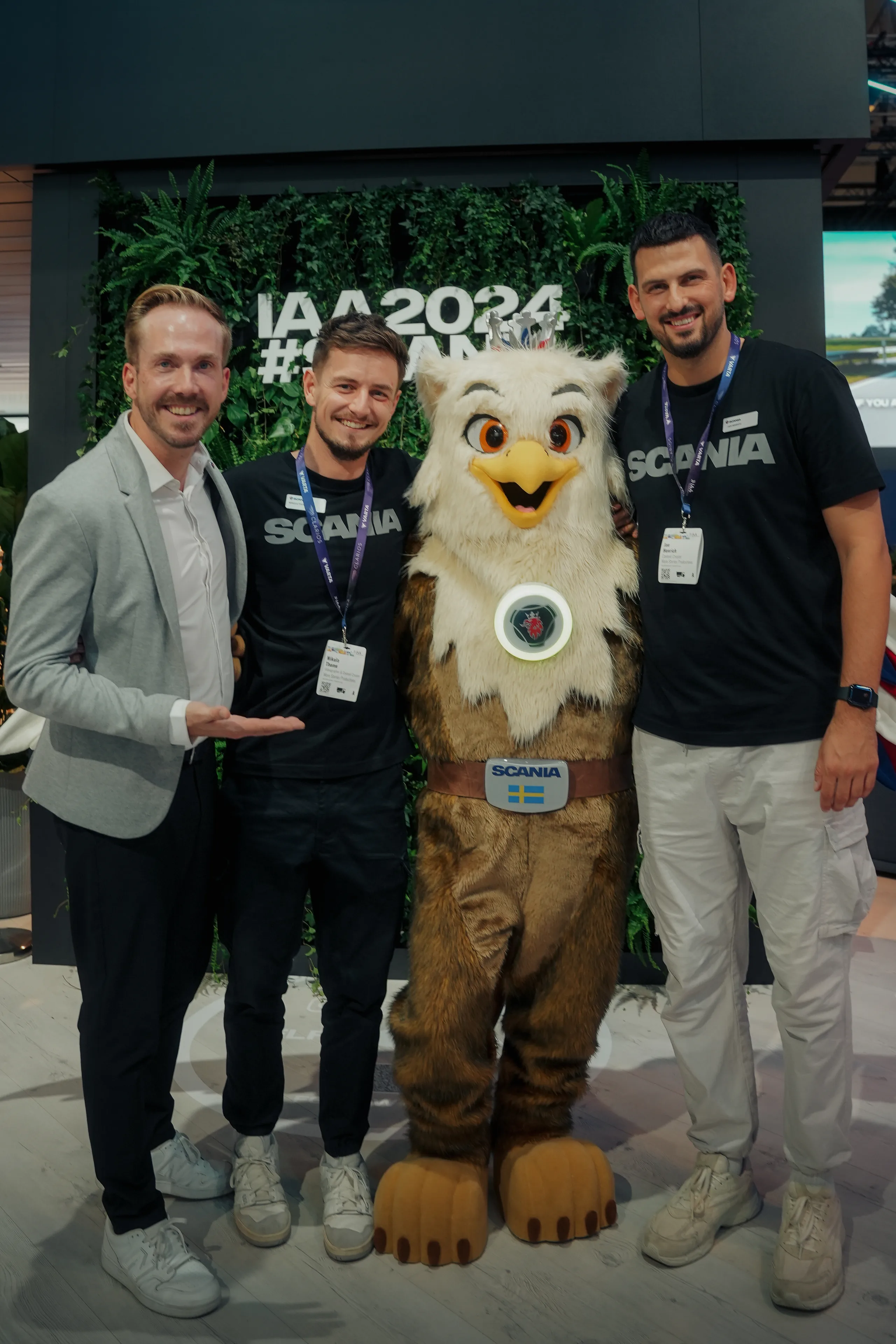 Felix Uhlig mit dem Standteam und dem Maskottchen vor der IAA-2024-Wand am Scania-Stand