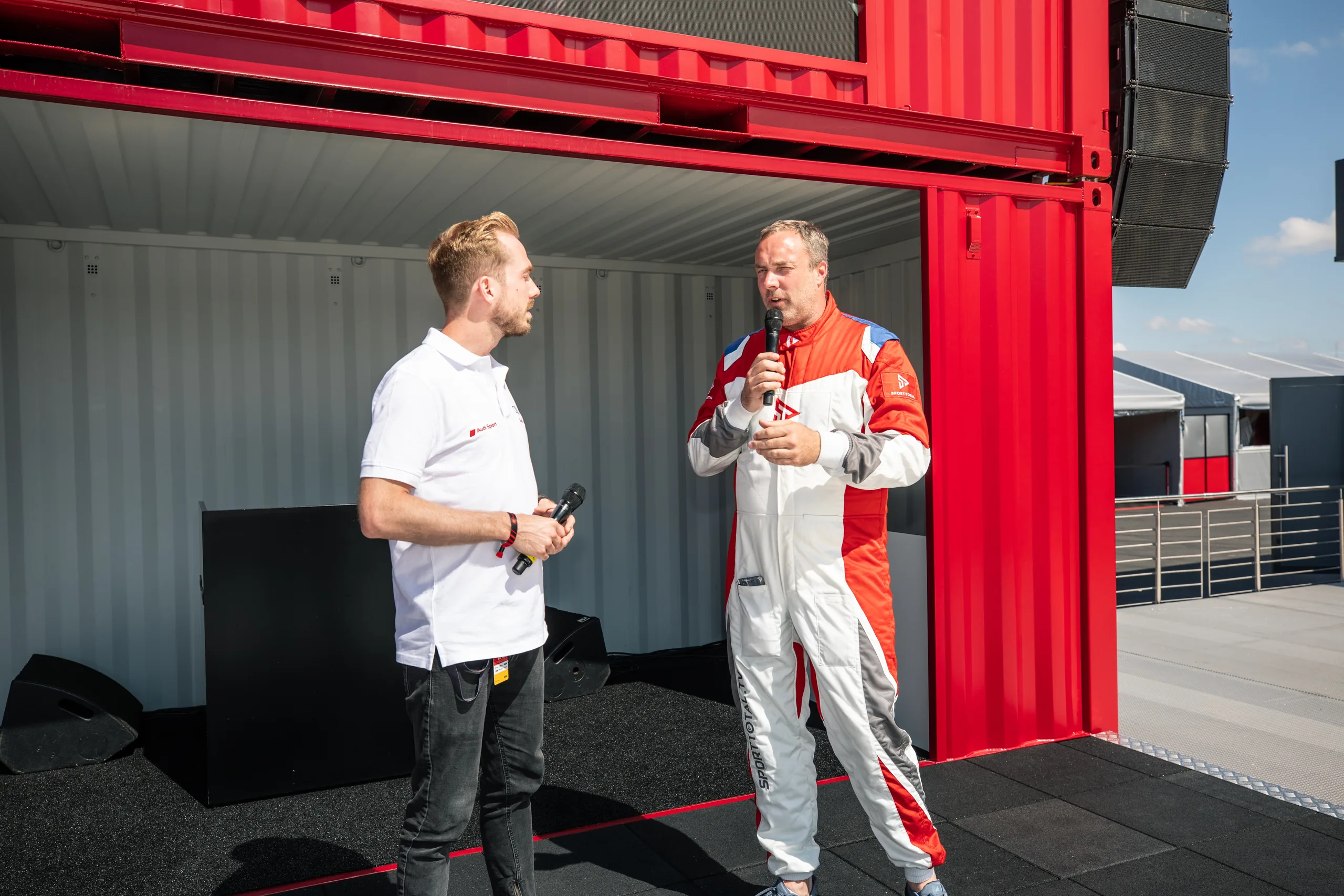 Felix Uhlig im Interview mit einem Fahrer im Rennanzug beim 24h-Rennen 2019 am Nürburgring