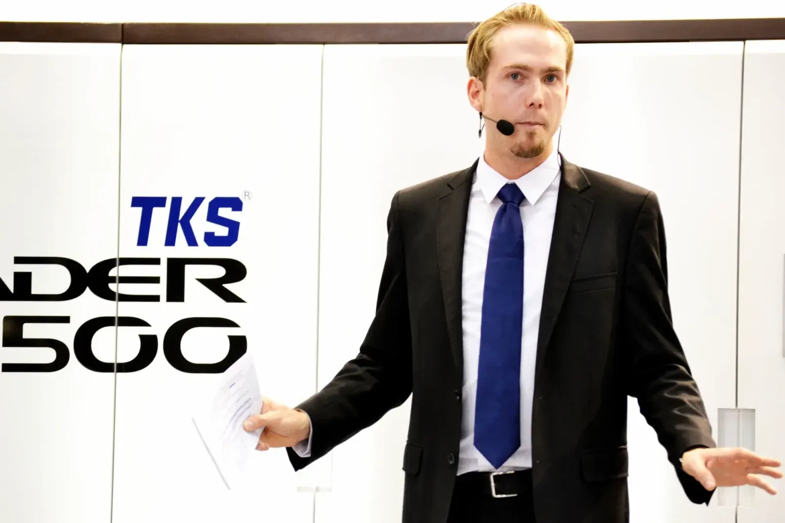 Felix Uhlig 2012 auf der drupa am Messestand von TKS, mit Headset und Moderationskarte