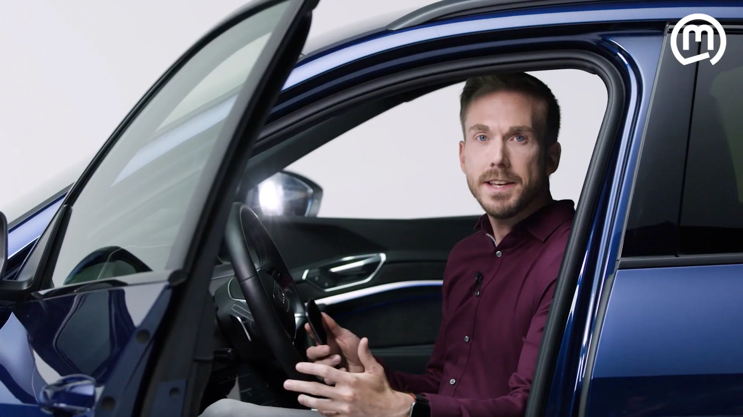 Felix Uhlig zeigt am Steuer eines Fahrzeugs, wie das Smartphone als Schlüssel für die Marquardt PnD3 dient