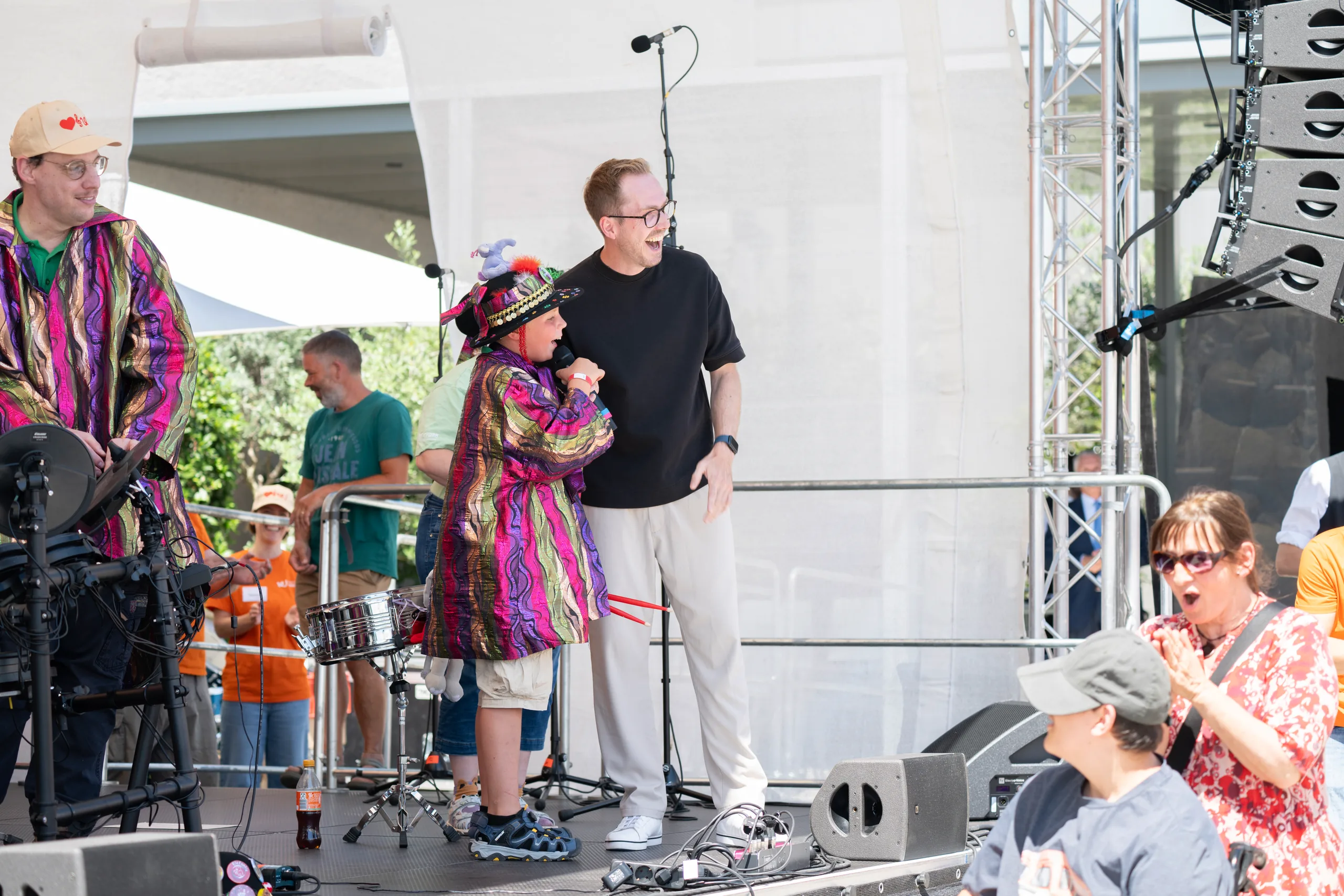 Moderator Felix Uhlig auf der Bühne des 7. Musikfests der Stiftung Würth mit einer Musikgruppe in bunten Kostümen
