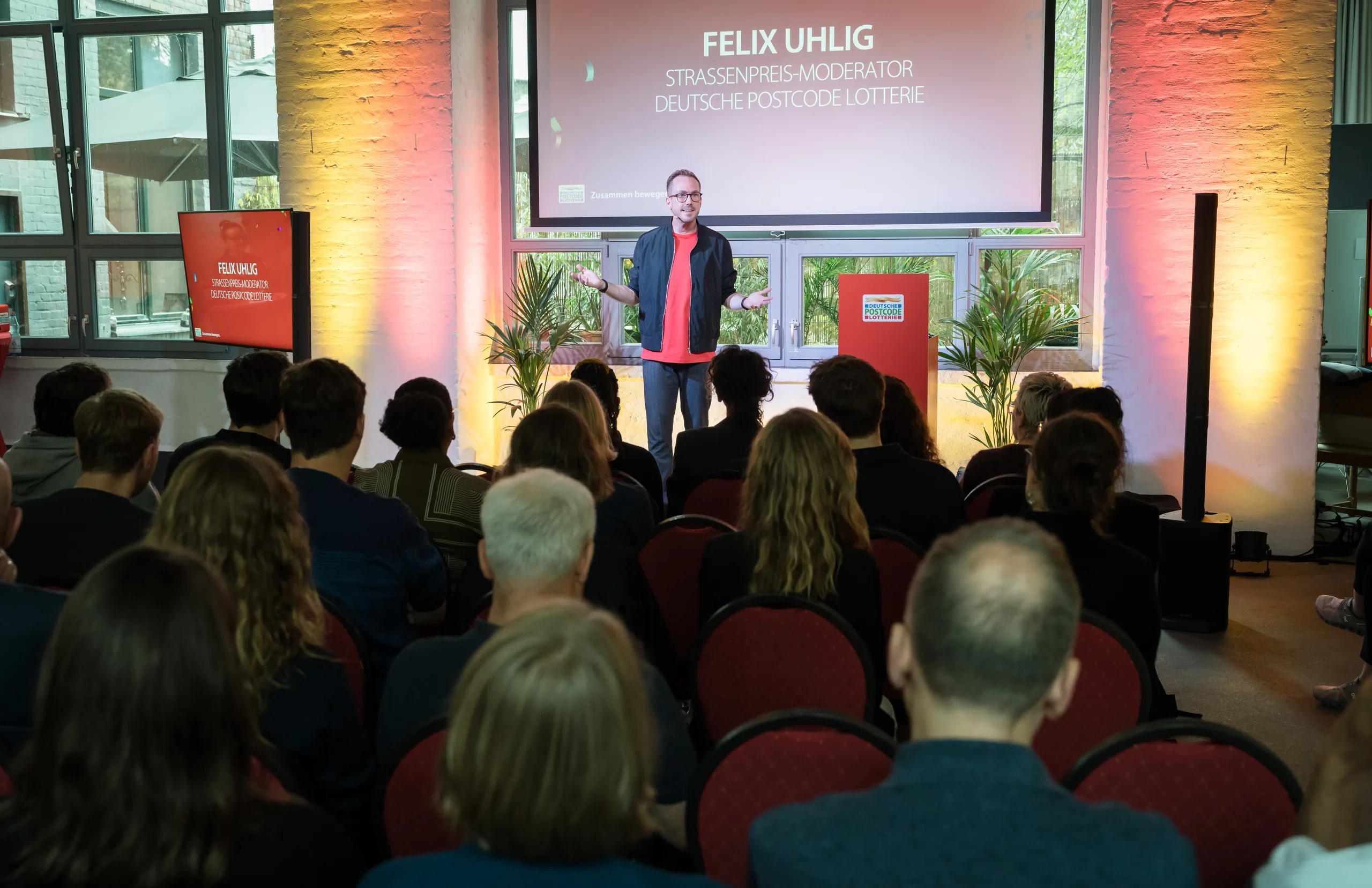 Blick aus dem Publikum auf Felix Uhlig beim Partnertreffen der Deutschen Postcode Lotterie 2025