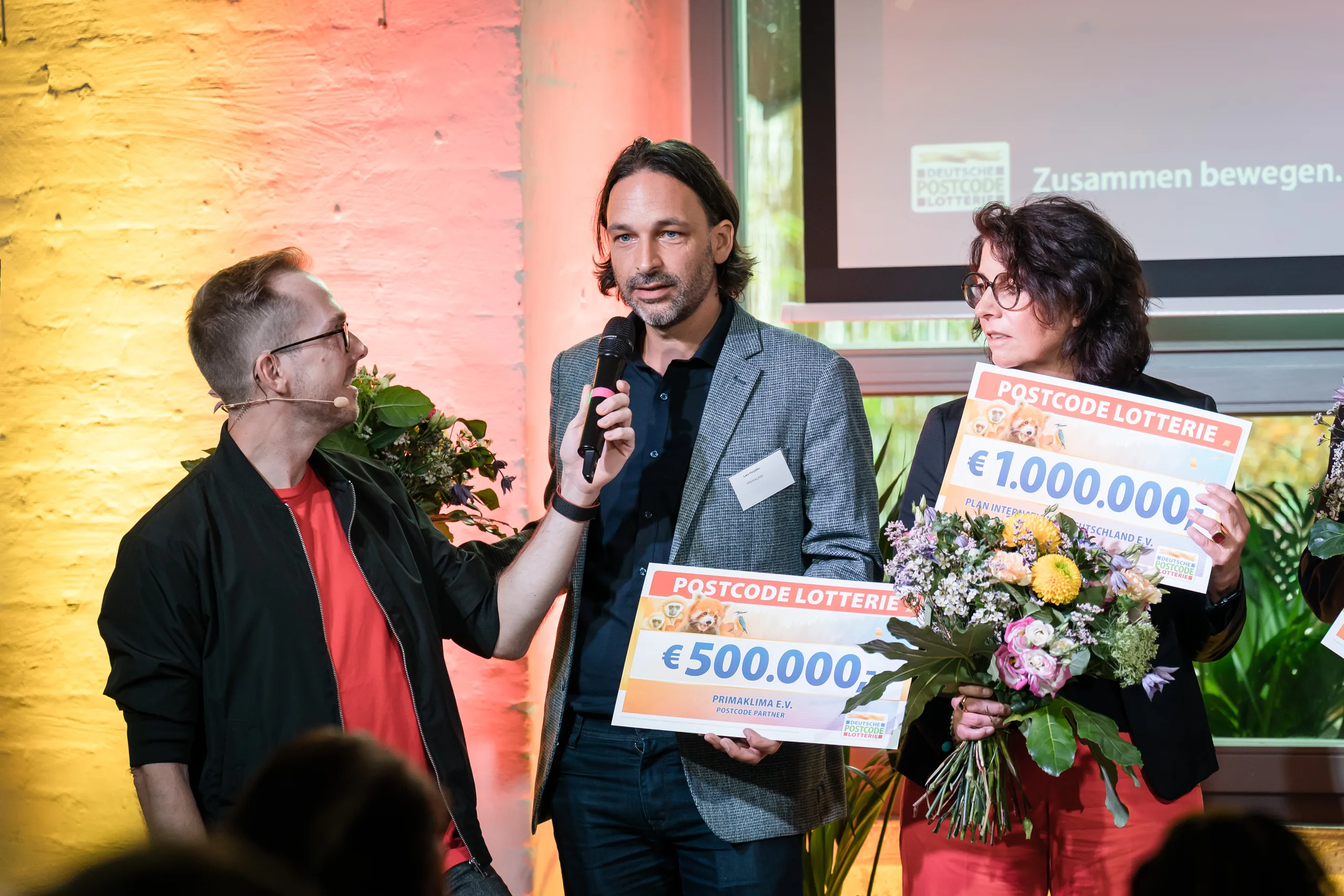 Übergabe der Förderschecks beim Postcode Partner Treffen 2025 in Berlin, Moderator Felix Uhlig mit dem Mikrofon