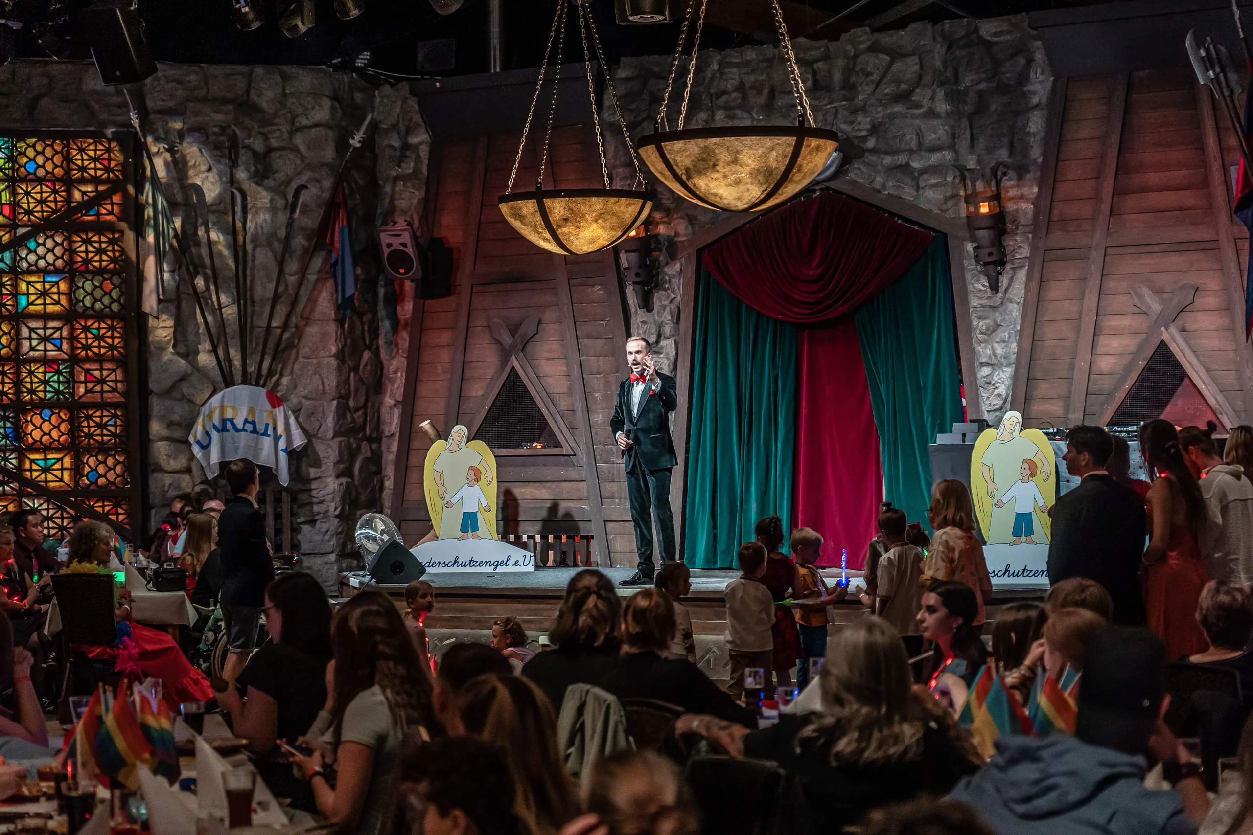 Blick über den vollen Saal der PSD Gala der Kinderschutzengel 2022 in Berlin, Felix Uhlig auf der Bühne