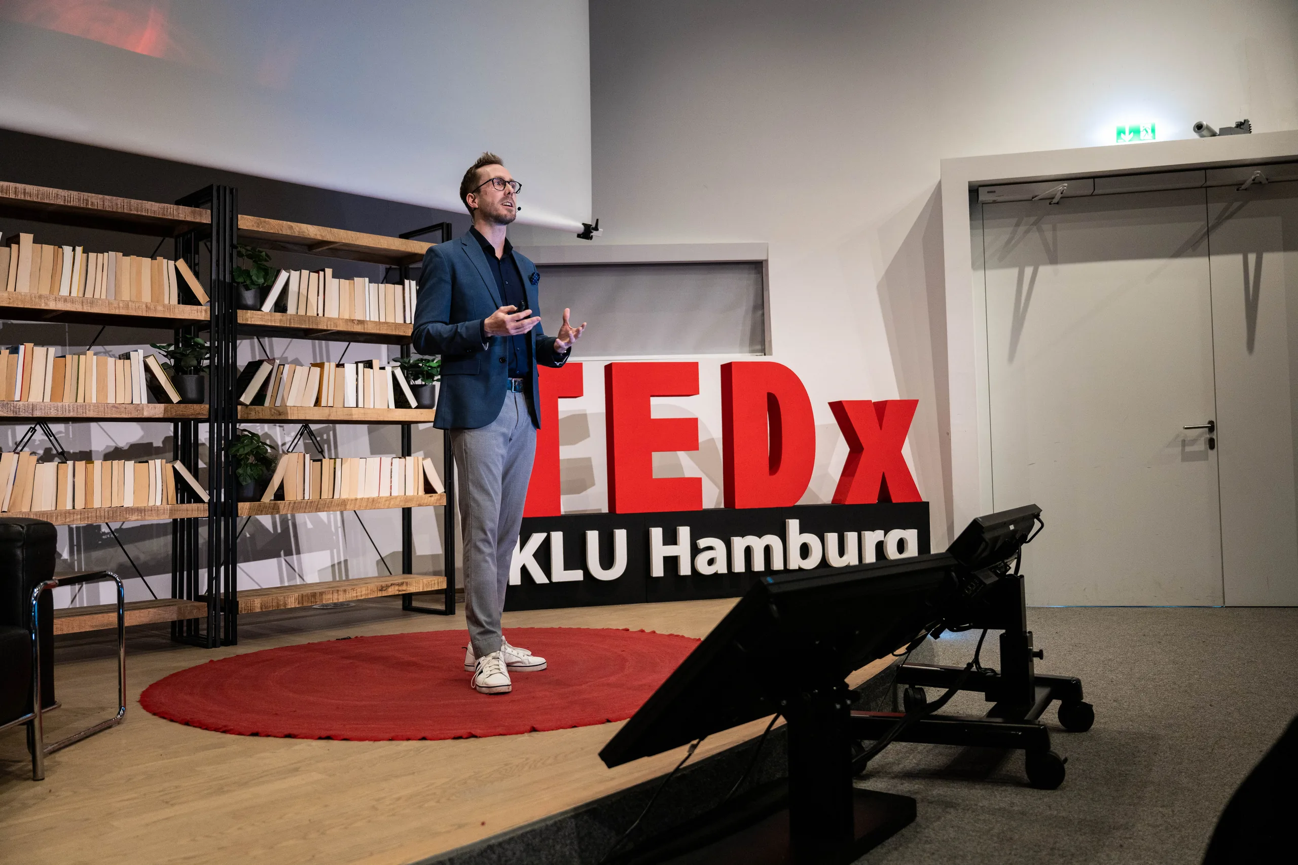 Moderator Felix Uhlig auf dem roten Kreis vor der TEDxKLU-Wand an der Kühne Logistics University in Hamburg