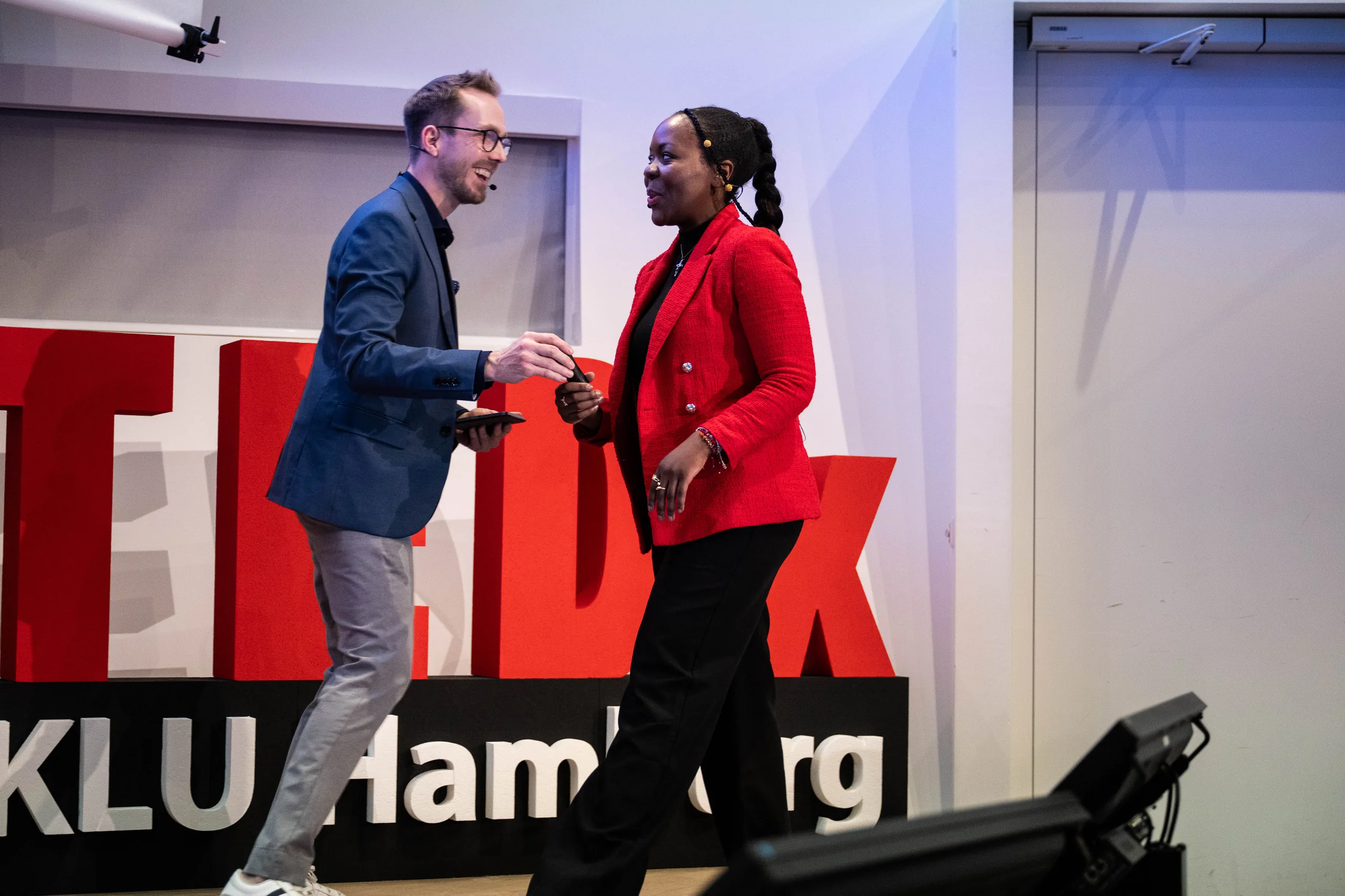 Moderator Felix Uhlig begrüßt eine Speakerin auf der Bühne von TEDxKLU Hamburg