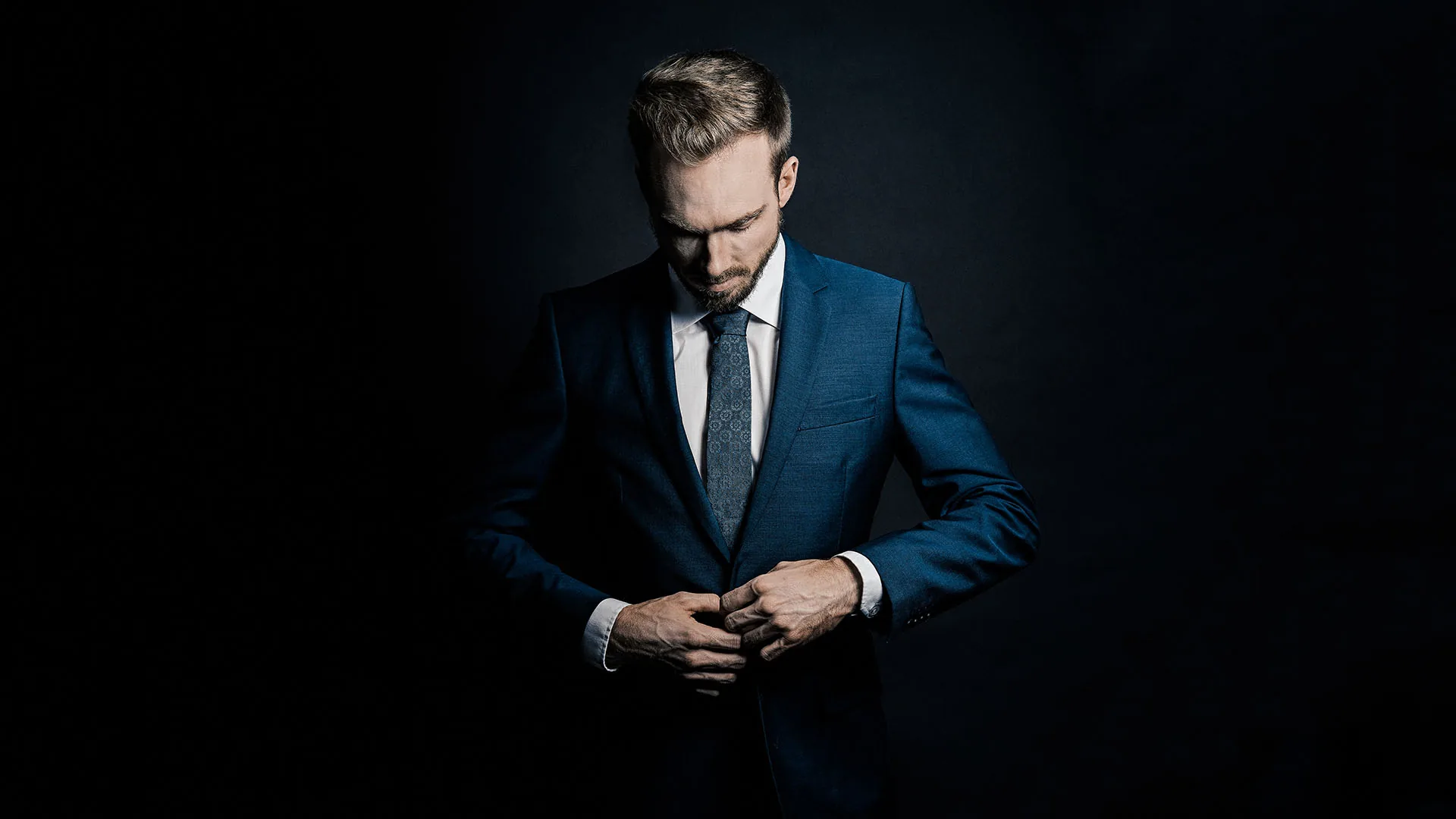 Felix Uhlig in a dark blue suit against a black background